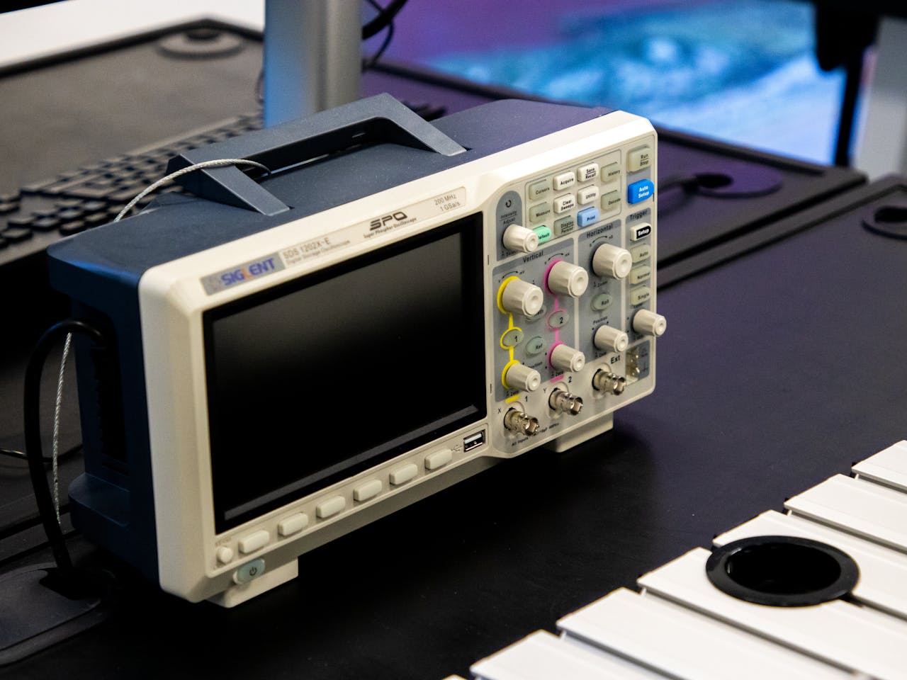 A digital oscilloscope on a laboratory workbench, showcasing modern electronic equipment.